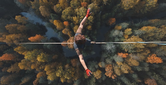 Highline over the forest. Rope walker walks on a rope at high altitude. Drone view.