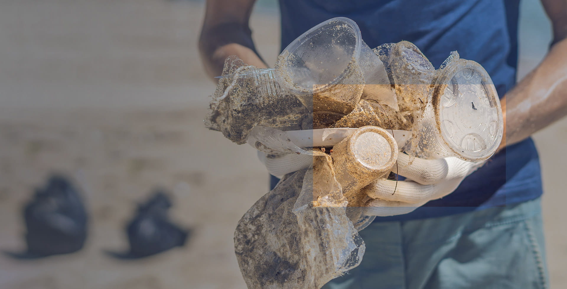 Man in gloves pick up plastic bags that pollute sea