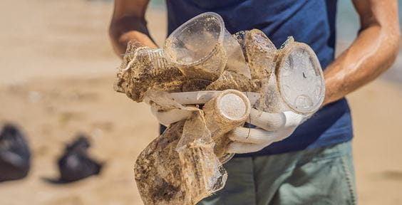 Man in gloves pick up plastic bags that pollute sea