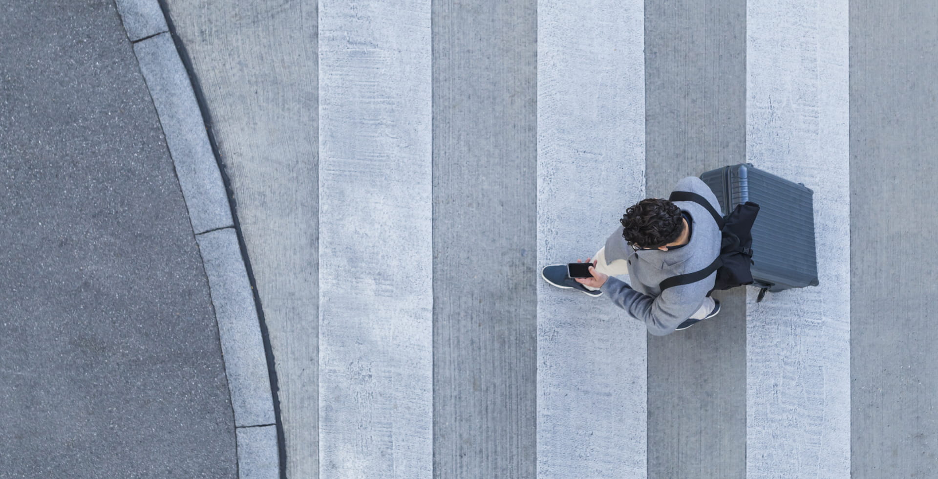 Man walking on crosswalk while looking at phone