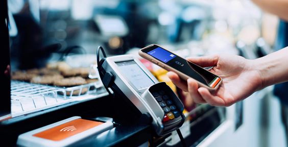 Image #alt close-up photo of a hand holding a phone next to a contacteless payment device in a shop