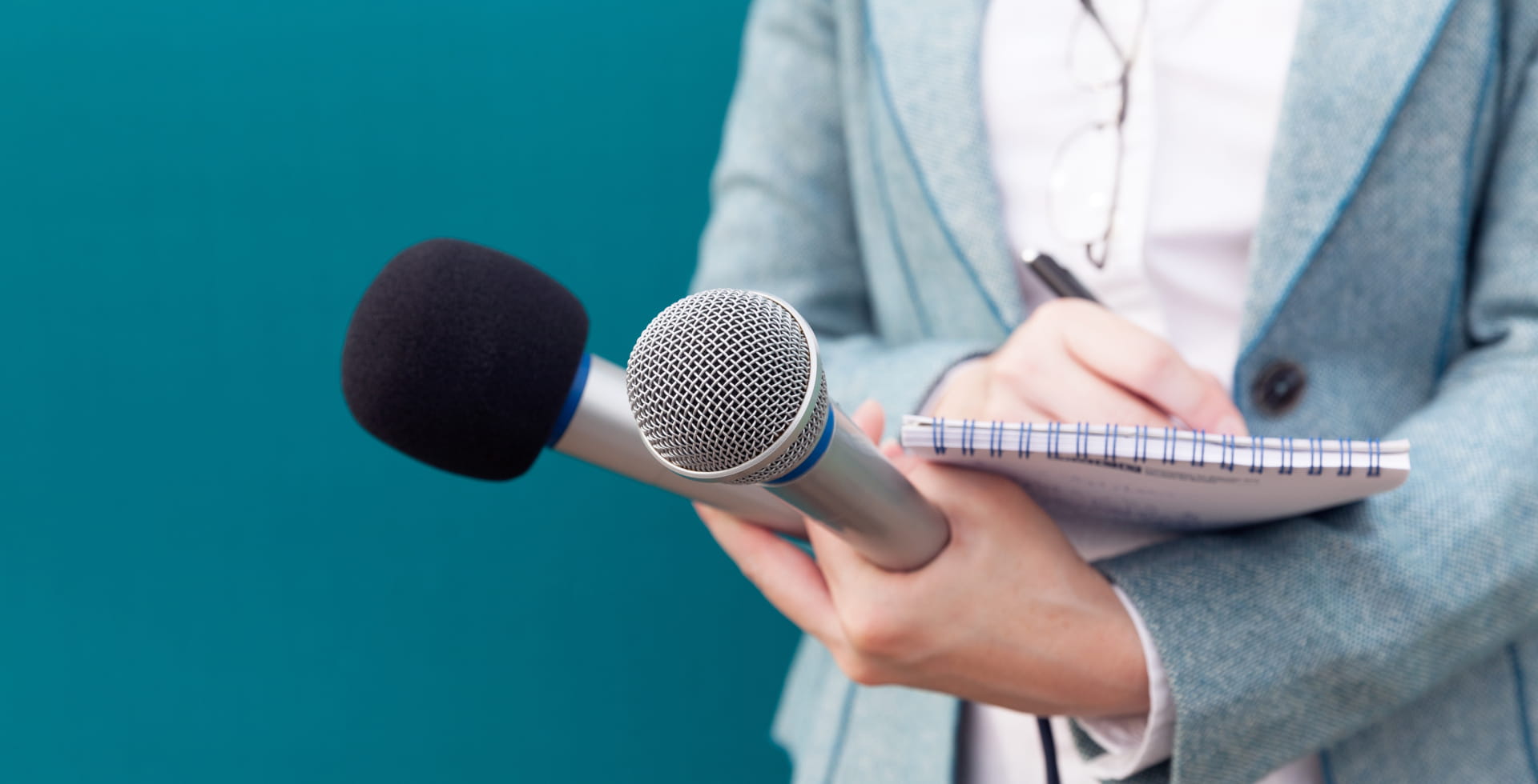 Reporter or TV journalist at news conference, holding microphone and writing notes
