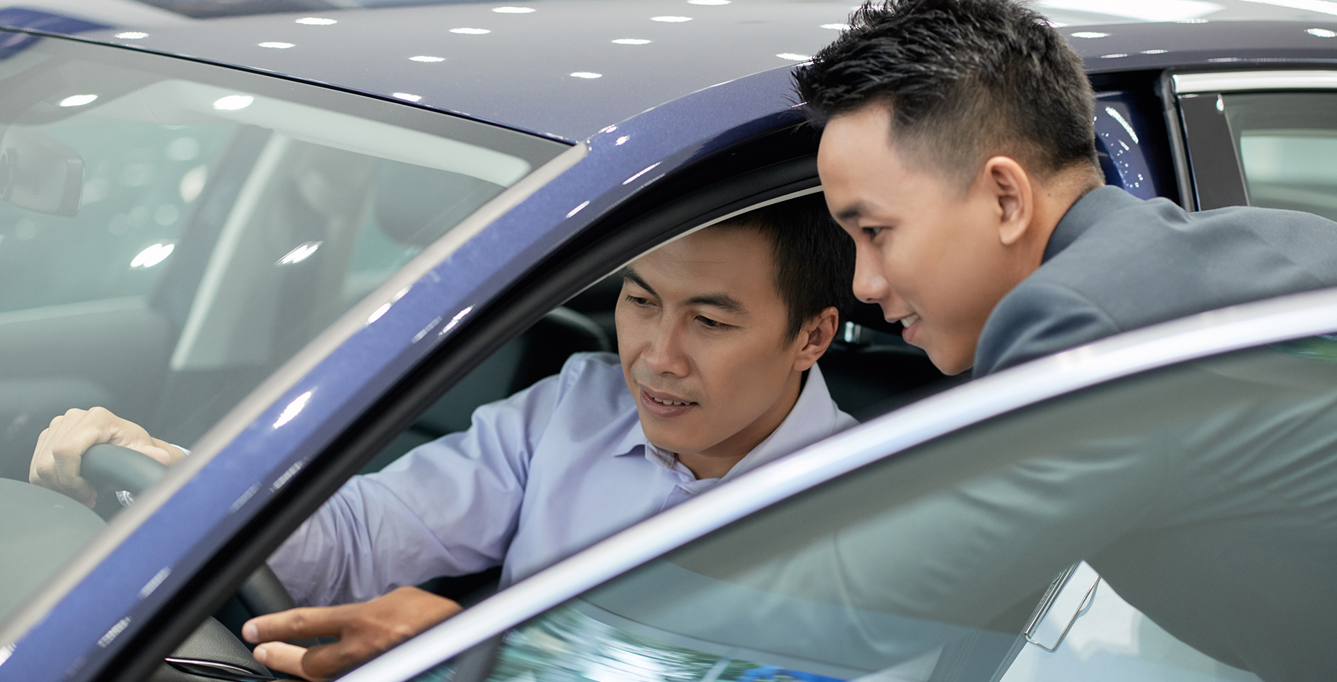 Chinese salesman and customer inspect a new car