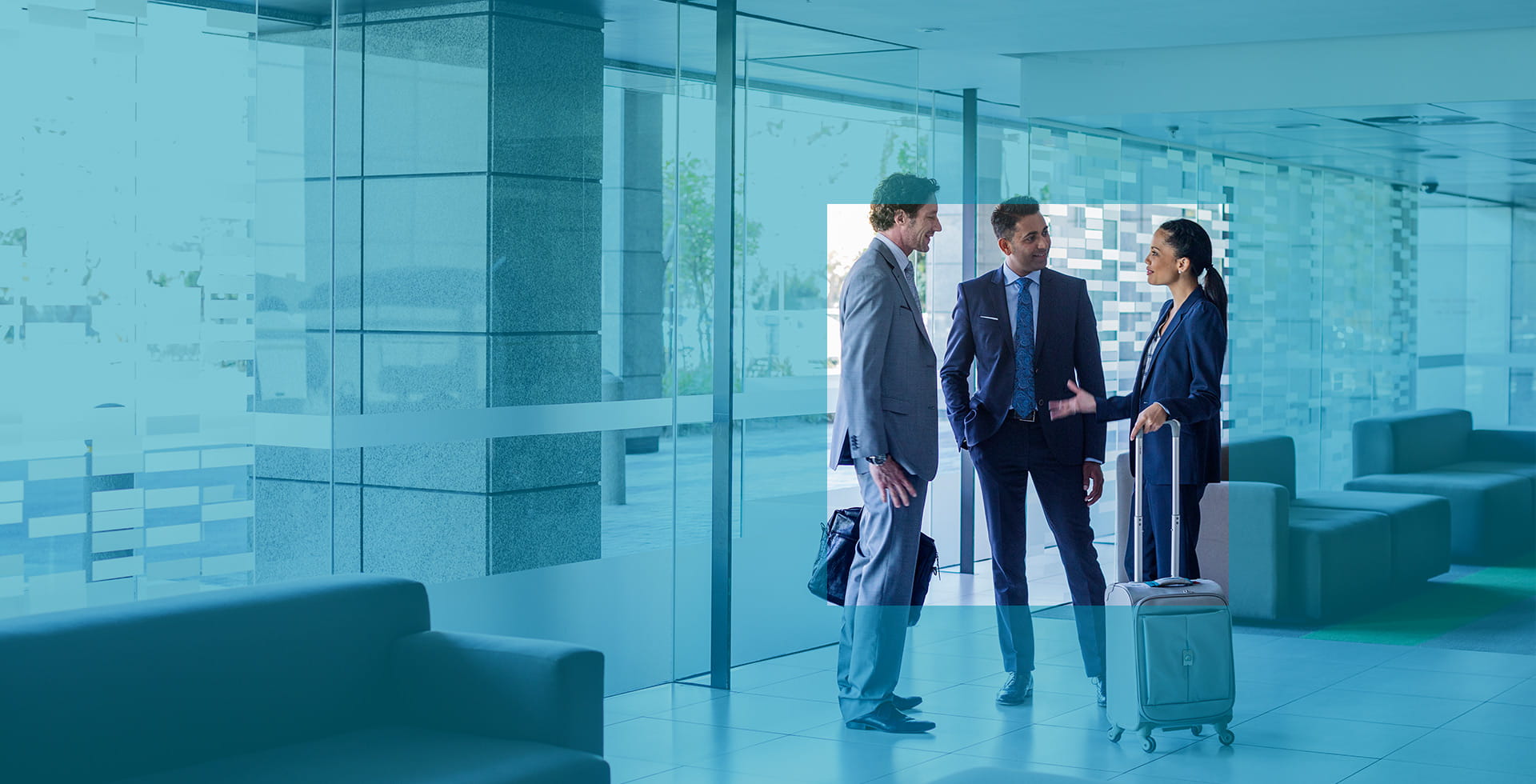 Three business people wait in a hotel lobby as part of corporate travel