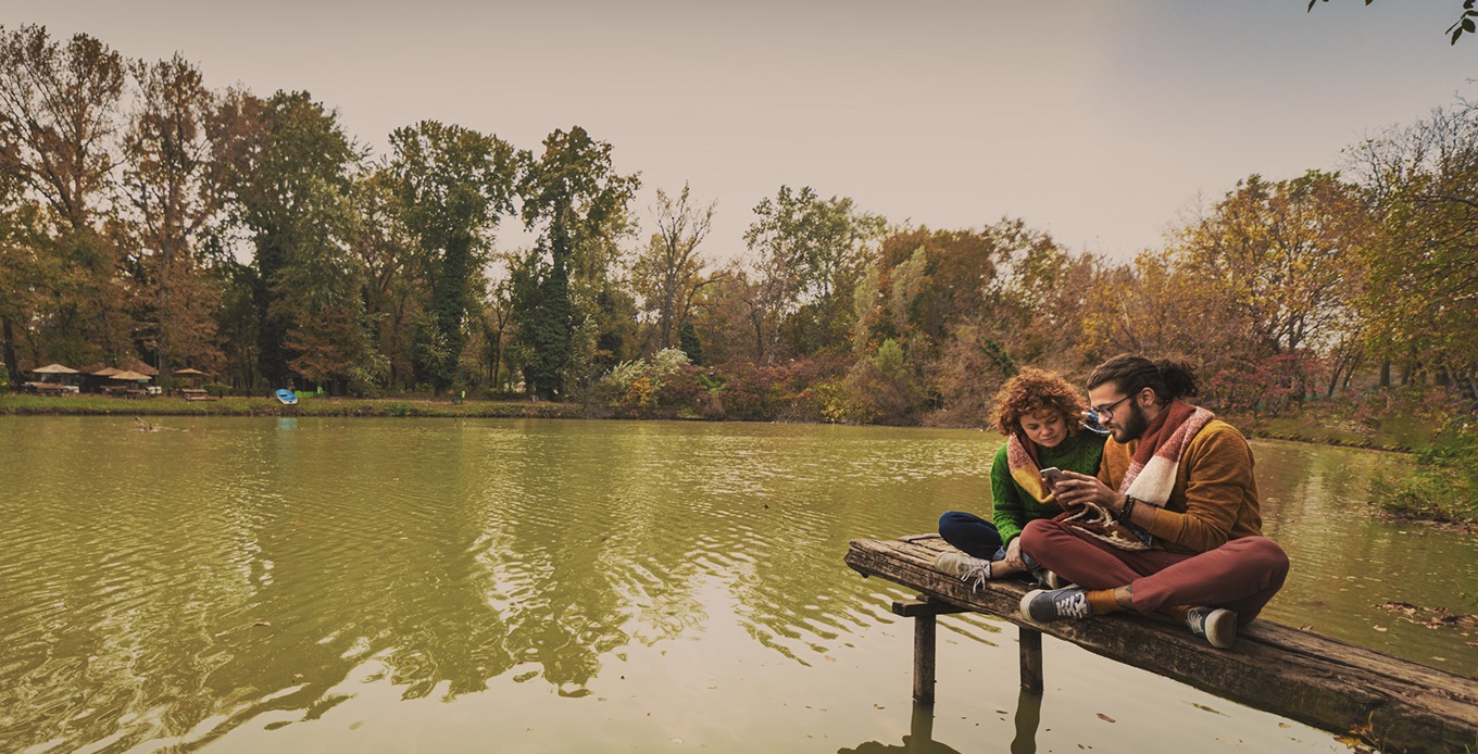 two people looking at a phone by the pond